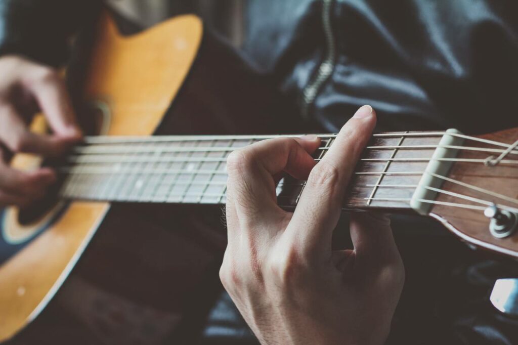 Homem toca música com pestana no violão