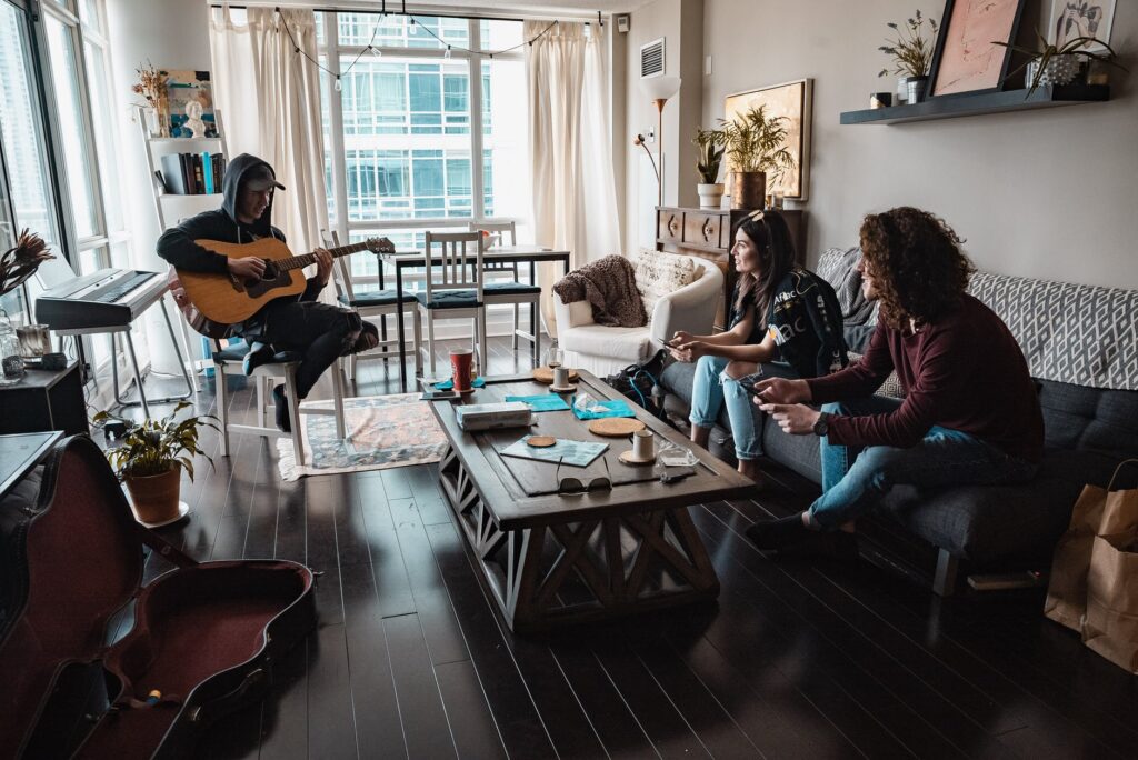 Músico tocando na frente de um casal de amigos é sinal de que há conhecimento sobre o tempo para aprender a tocar violão