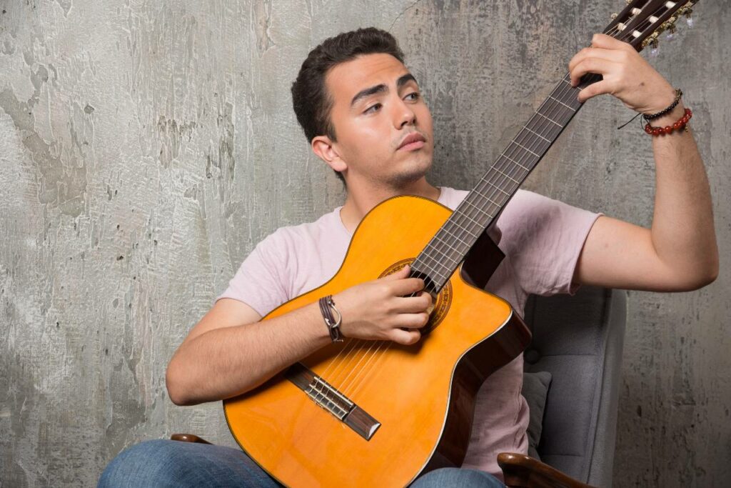 Músico jovem tocando dedilhado no violão