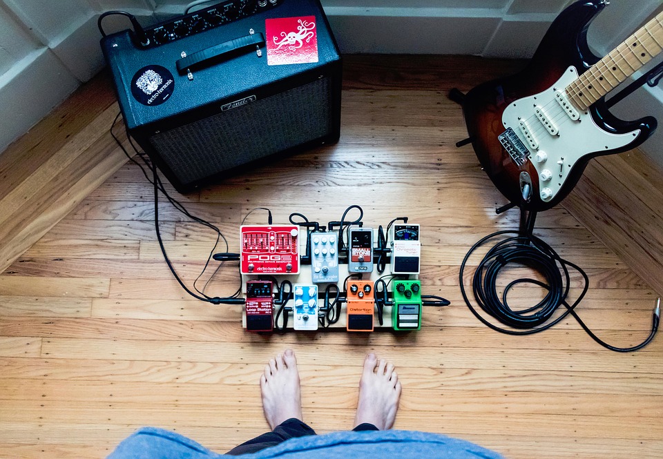 Guitarrista observa seu set completo: pedalboard, guitarra, amplificador e cabos