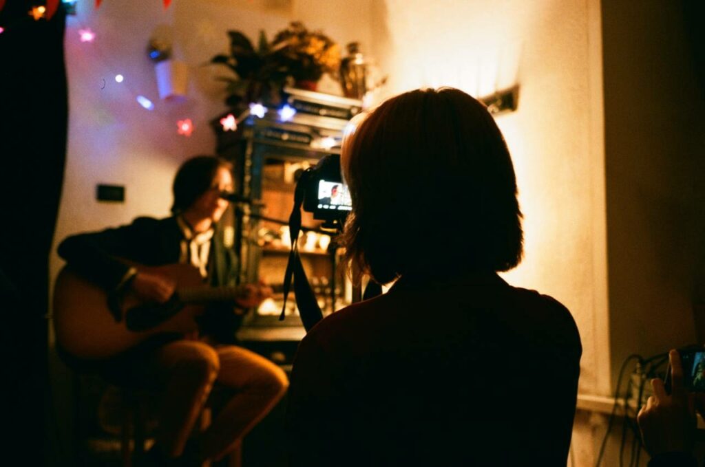 Mulher filma músico tocando no formato voz e violão