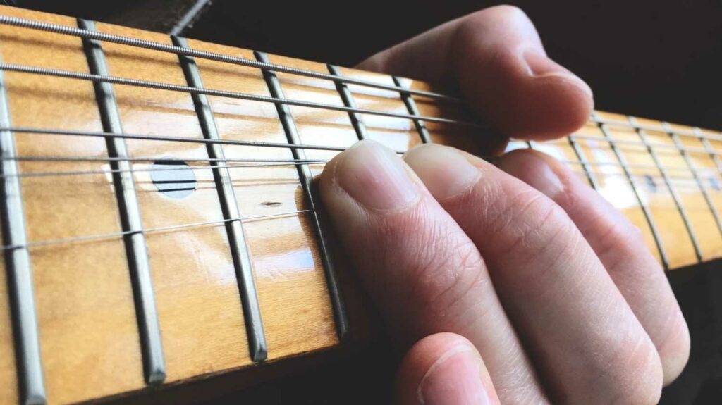 Dedos da mão esquerda de um guitarrista executam um dos tipos de bends na guitarra  Stratocaster