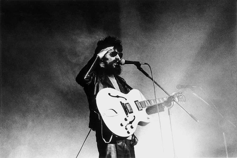 Raul Seixas em show cantando e tocando guitarra em foto em preto e branco