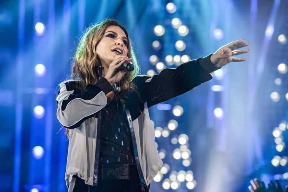 Aline Barros cantando em show estendendo o braço