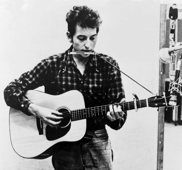 Bob Dylan toca violão e  gaita ao mesmo tempo