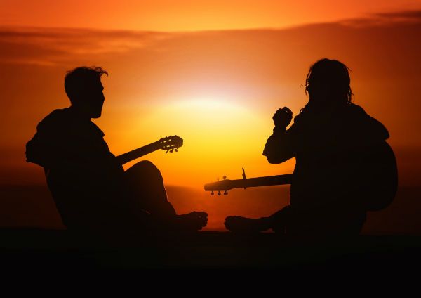 Dupla tocando guitarra frente a la puesta del sol