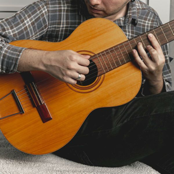 Hombre joven tocando la guitarra acústica