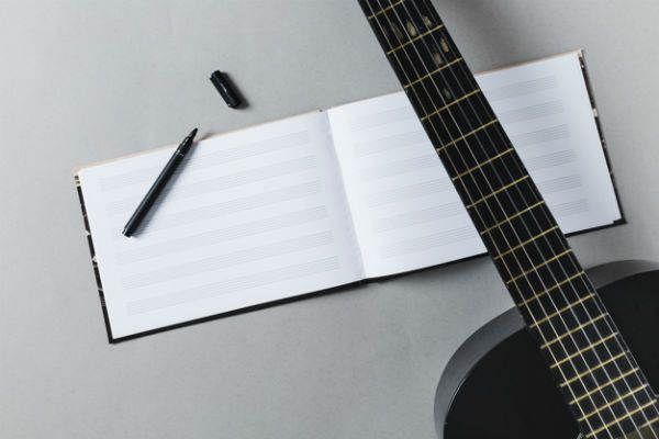 Cuaderno de música, guitarra  y lapicero: material de estudio musical