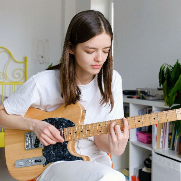 mulher_guitarrista Garota estudante de guitarra toca um acorde com pestana em sua telecaster