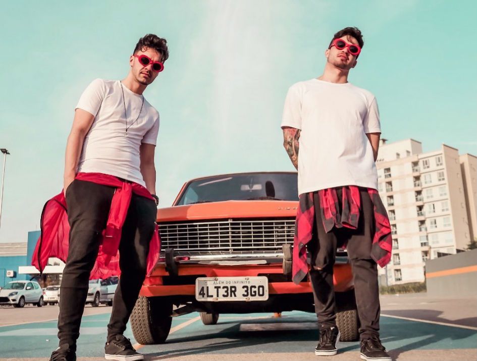 Os membros da dupla ALTER EGO posam em frente a um carro laranja