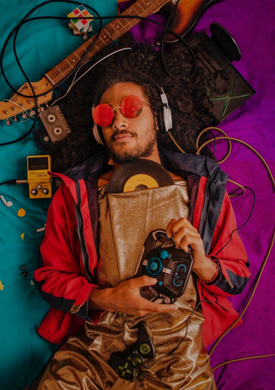Homem negro, surando controle de videogame e rodeado por equimanetos de composição musical